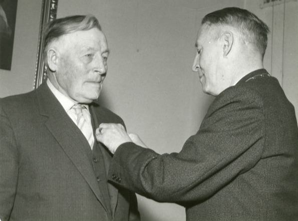 Bernard Huinink krijgt koninklijke onderscheiding opgespeld door burgemeester E.S. van Veen